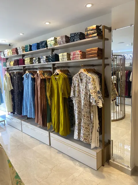 Wall shelving and hanging rails along the showroom wall under recessed ceiling lights