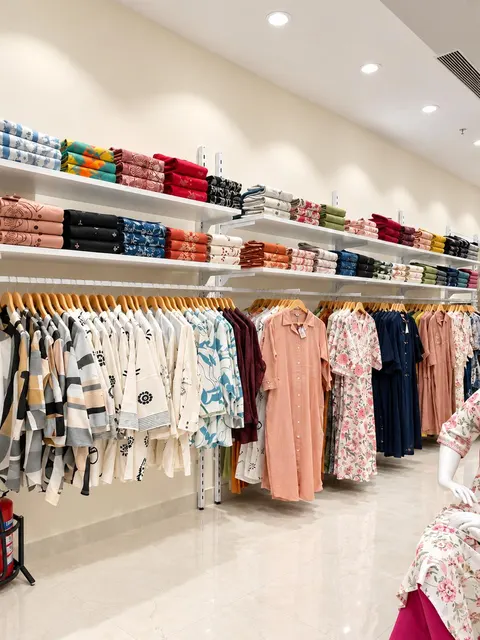 White wall shelving with folded stock above and garment rails below