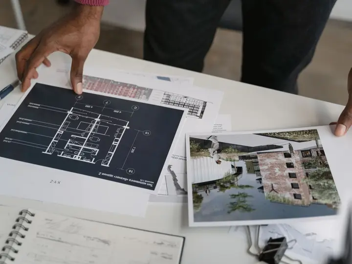 Hands reviewing floor plans and a building render